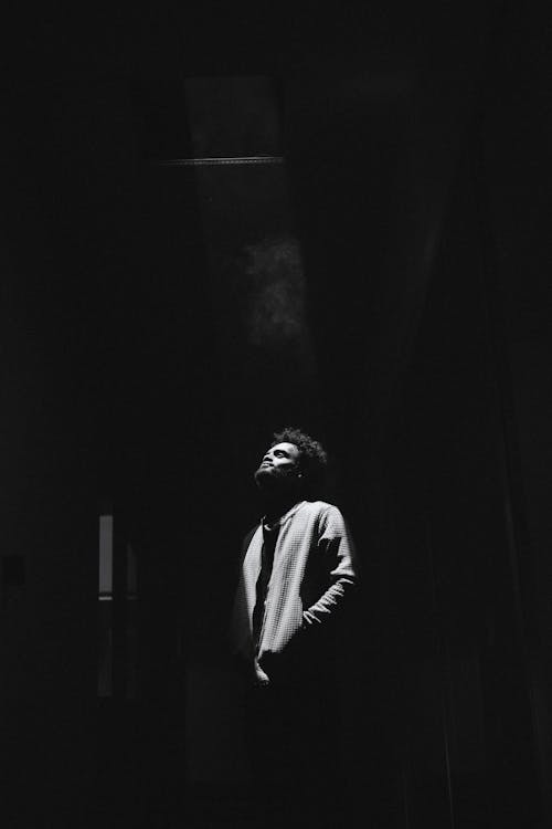 Man in Spotlight Standing in Dark Corridor