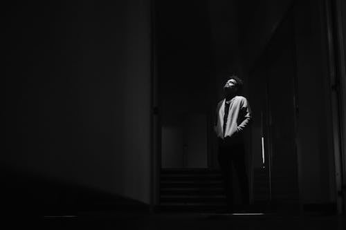 Man Standing and Looking Up in Dark