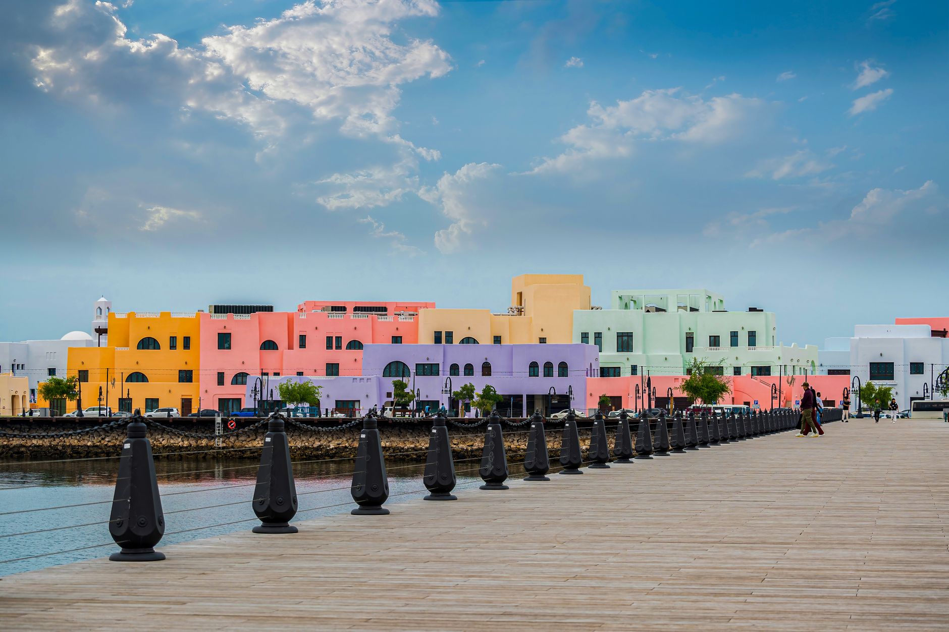 Vibrant pastel-colored buildings along Doha's waterfront, showcasing unique architectural style.