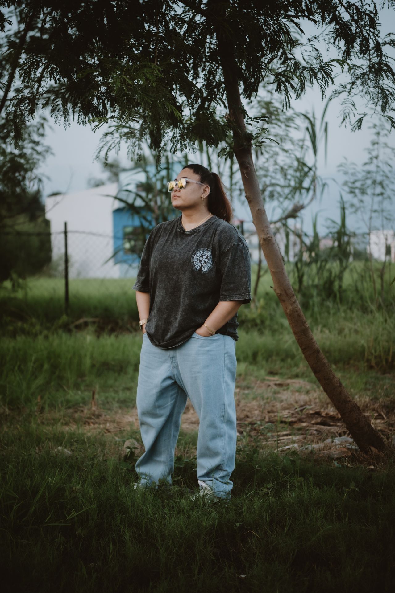 Woman in an oversized dark graphic tee, baggy jeans and sunglasses