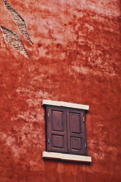 A Window with Wooden Shutters in a Red Building 