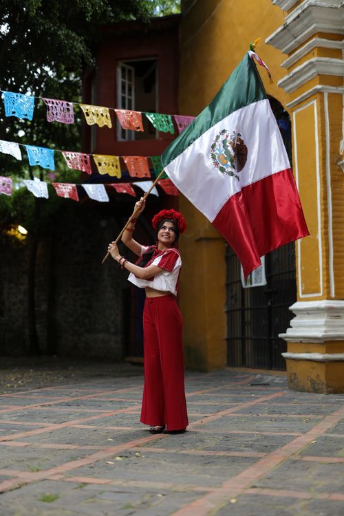 Free Woman in traditional attire celebrating Mexican culture outdoors with a flag. Stock Photo