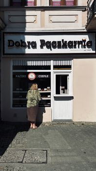 Woman browsing a bakery display in an urban setting on a sunny day.