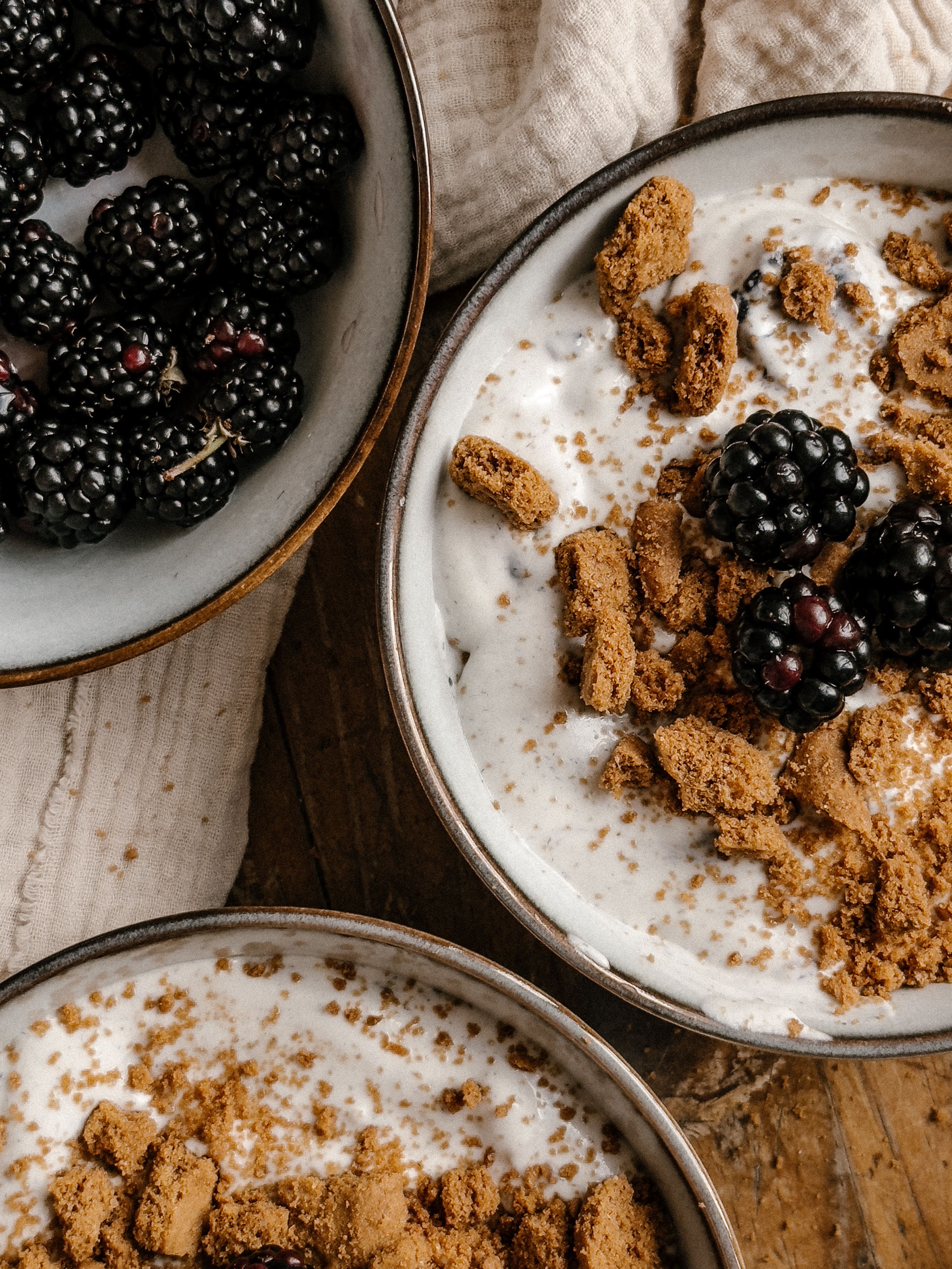 Top view of yogurt with fresh blackberries and crumbled biscuits, creating a healthy and delicious breakfast or snack option.