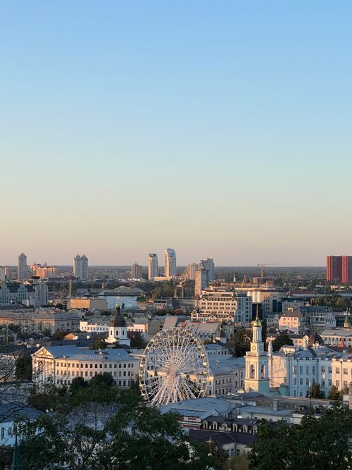 Free A scenic view of Kyiv cityscape featuring a Ferris wheel at sunset, highlighting urban architecture. Stock Photo