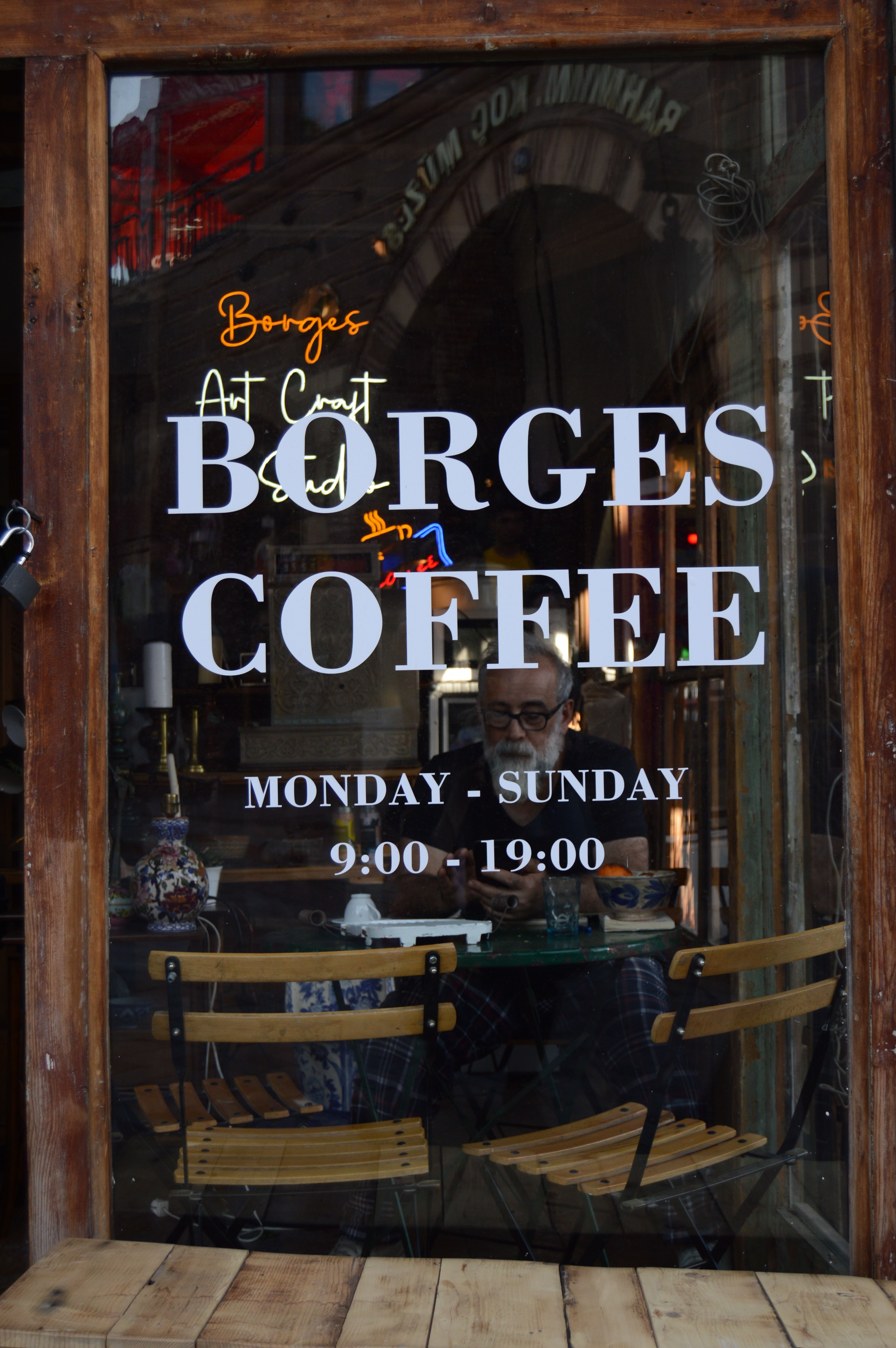 Inviting café window view with chairs and reflections, promoting coffee shop ambiance.