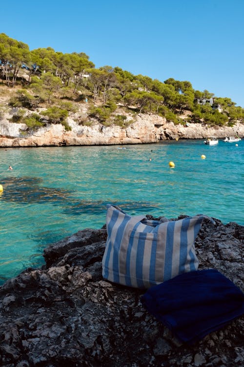 A Bag and Towel Lying on the Rock on the Shore