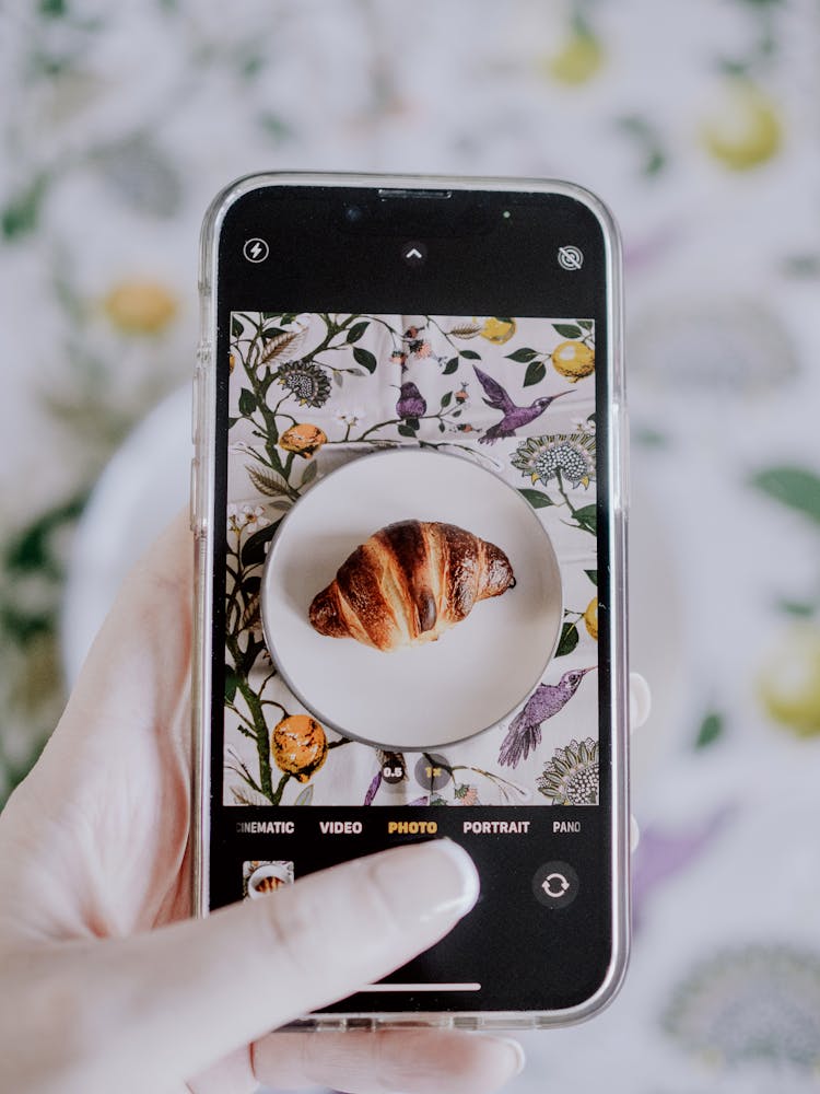 Woman Hand Taking Pictures Of Croissant With Smartphone