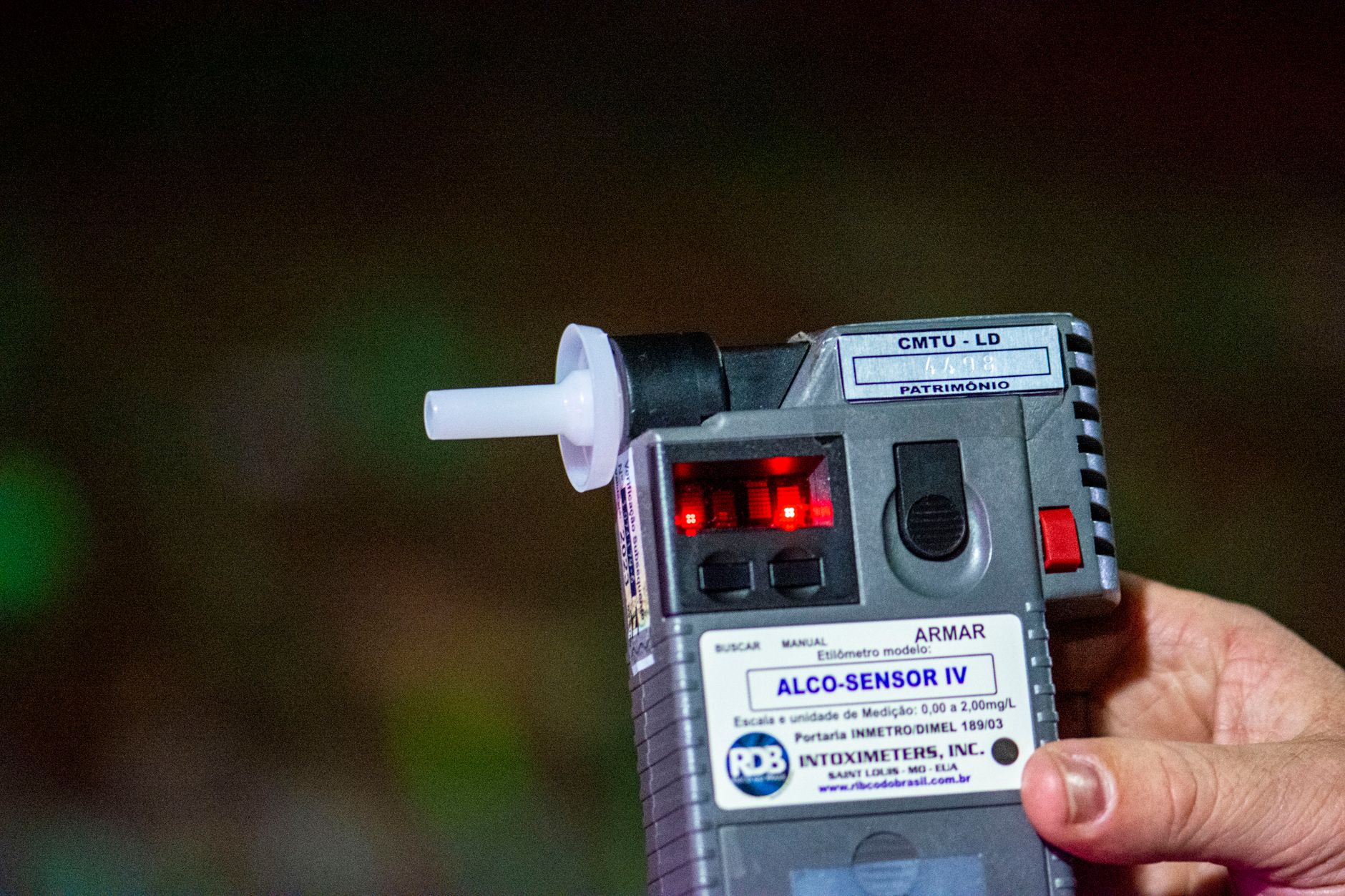 Detailed close-up of Alco-Sensor IV breathalyzer device held by a person outdoors in Londrina, Brazil.