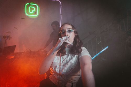 Free Vibrant club performance featuring a singer and DJ with neon lighting and smoke effects. Stock Photo