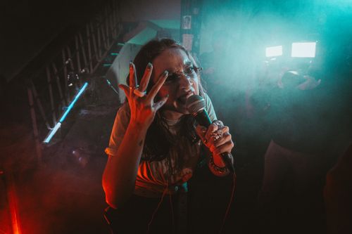 Free Dynamic singer performing in a nightclub with vibrant lighting and expressive gestures. Stock Photo