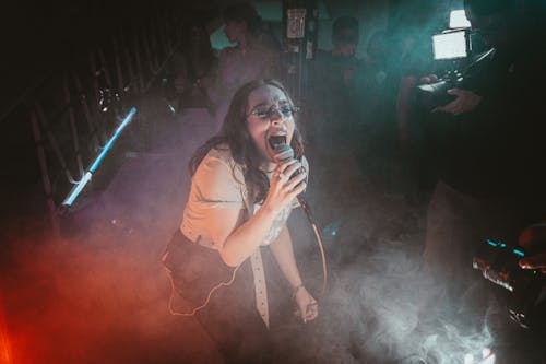 Photo of a Singer Performing on a Stage with Smoke