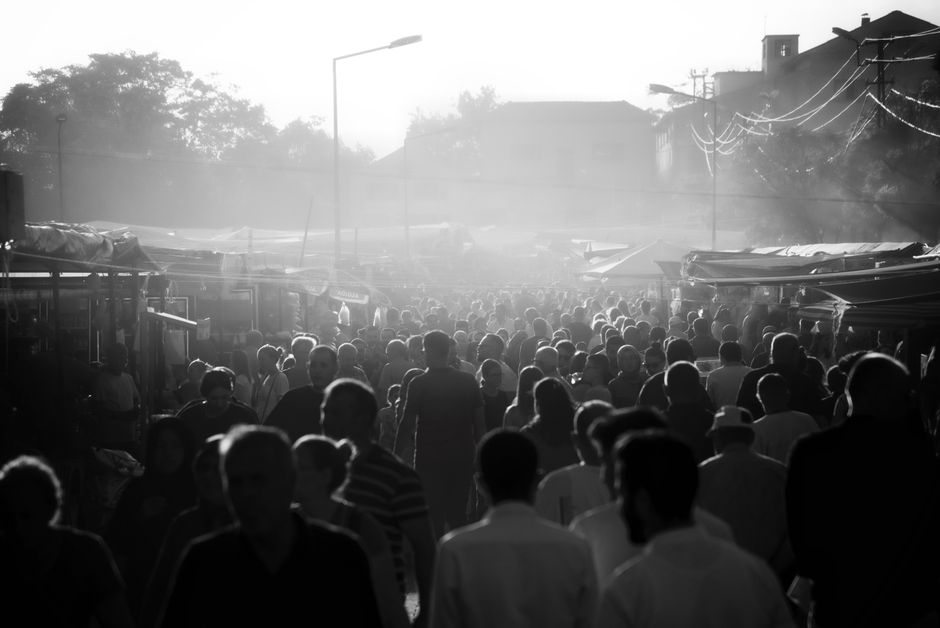 Monochrome photo of a crowded market street with fog and silhouettes of people.