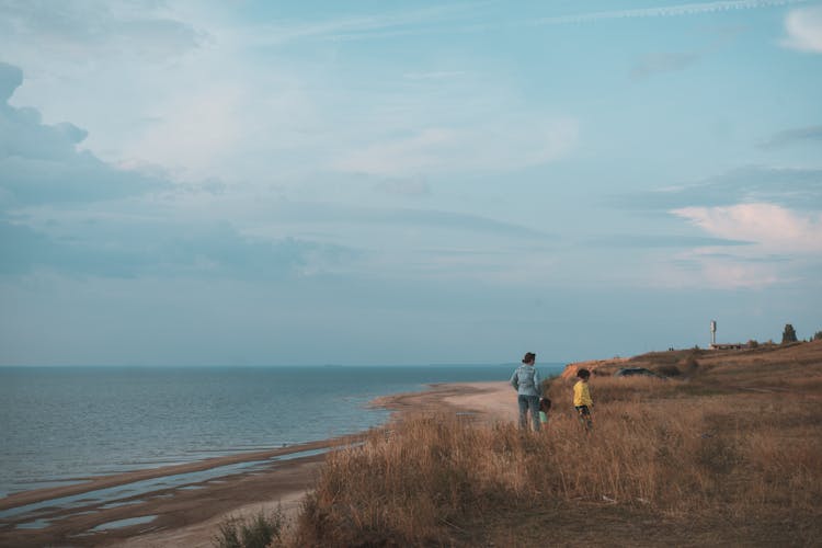 Woman With Children Standing On The Beach 