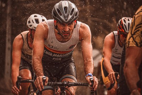 Free Determined athletes compete in a rain-soaked cycling race, pushing through with endurance. Stock Photo