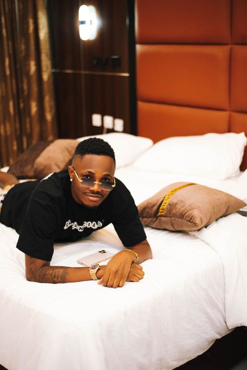 Free Man relaxing on a luxurious hotel bed, wearing sunglasses and casual attire, embracing leisure and comfort. Stock Photo