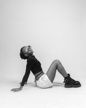 Black woman modeling fashion in a minimalist white studio.
