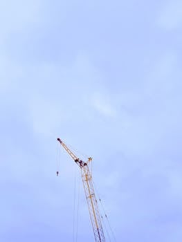 Tall construction crane against a blue sky with scattered clouds, providing ample copy space.