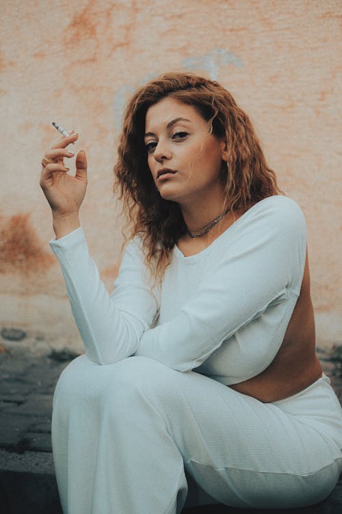 Woman Sitting on Curbside Smoking Cigarette
