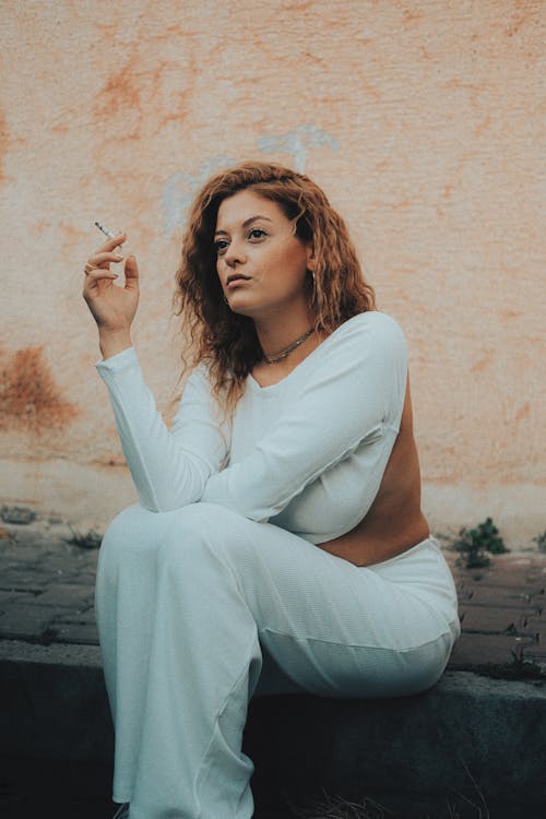 Young Woman Sitting Outside and Smoking a Cigarette