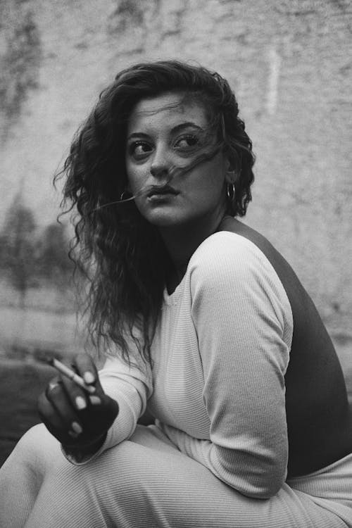 Young Woman Sitting Outside and Smoking a Cigarette
