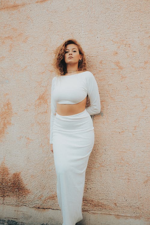 Woman in White Outfit Standing under Wall