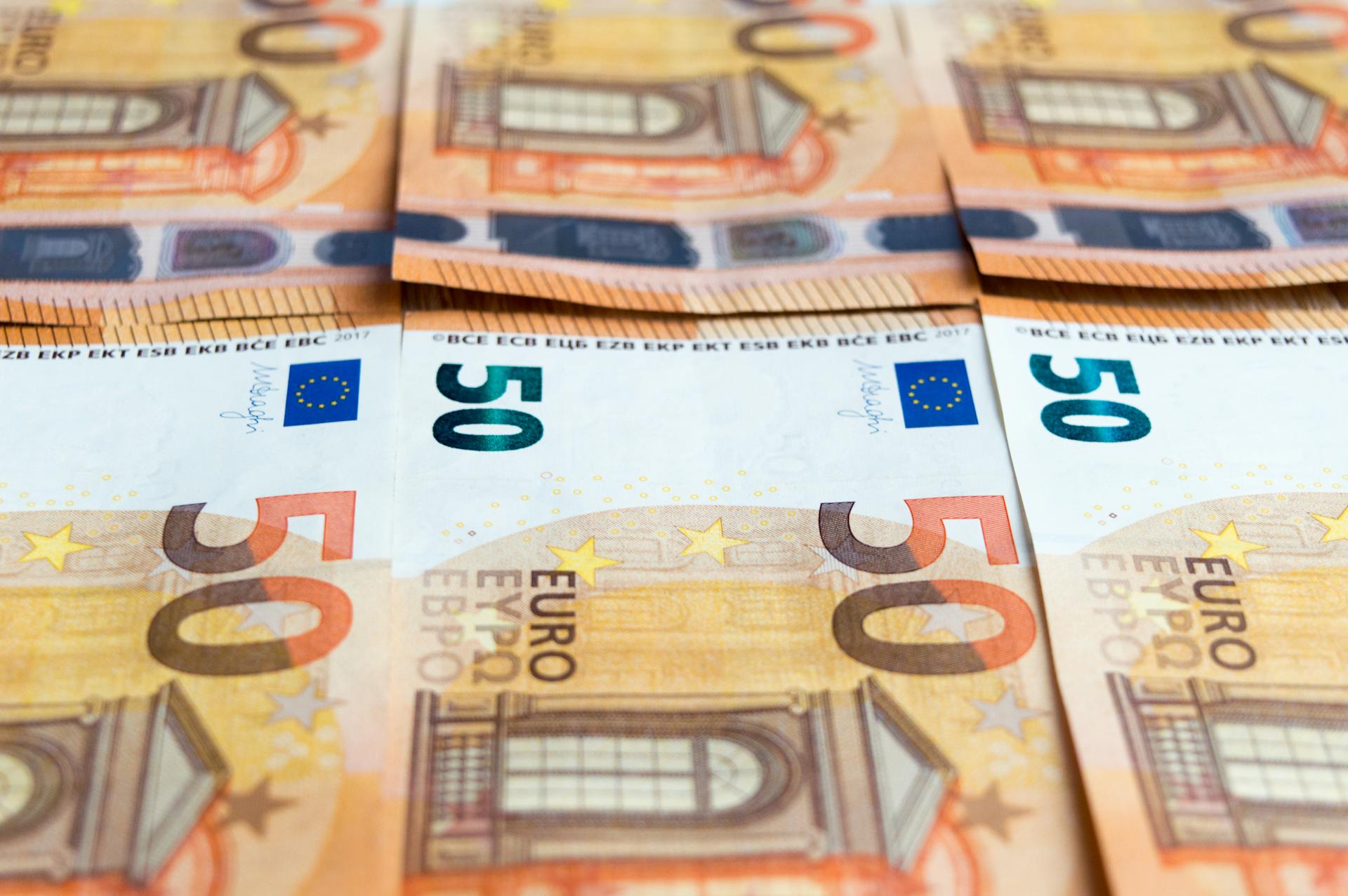 Detailed image of multiple 50 Euro bills stacked, showcasing currency design.