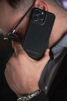 Close-up of a man using a luxury leather phone case, embodying style and modern technology.