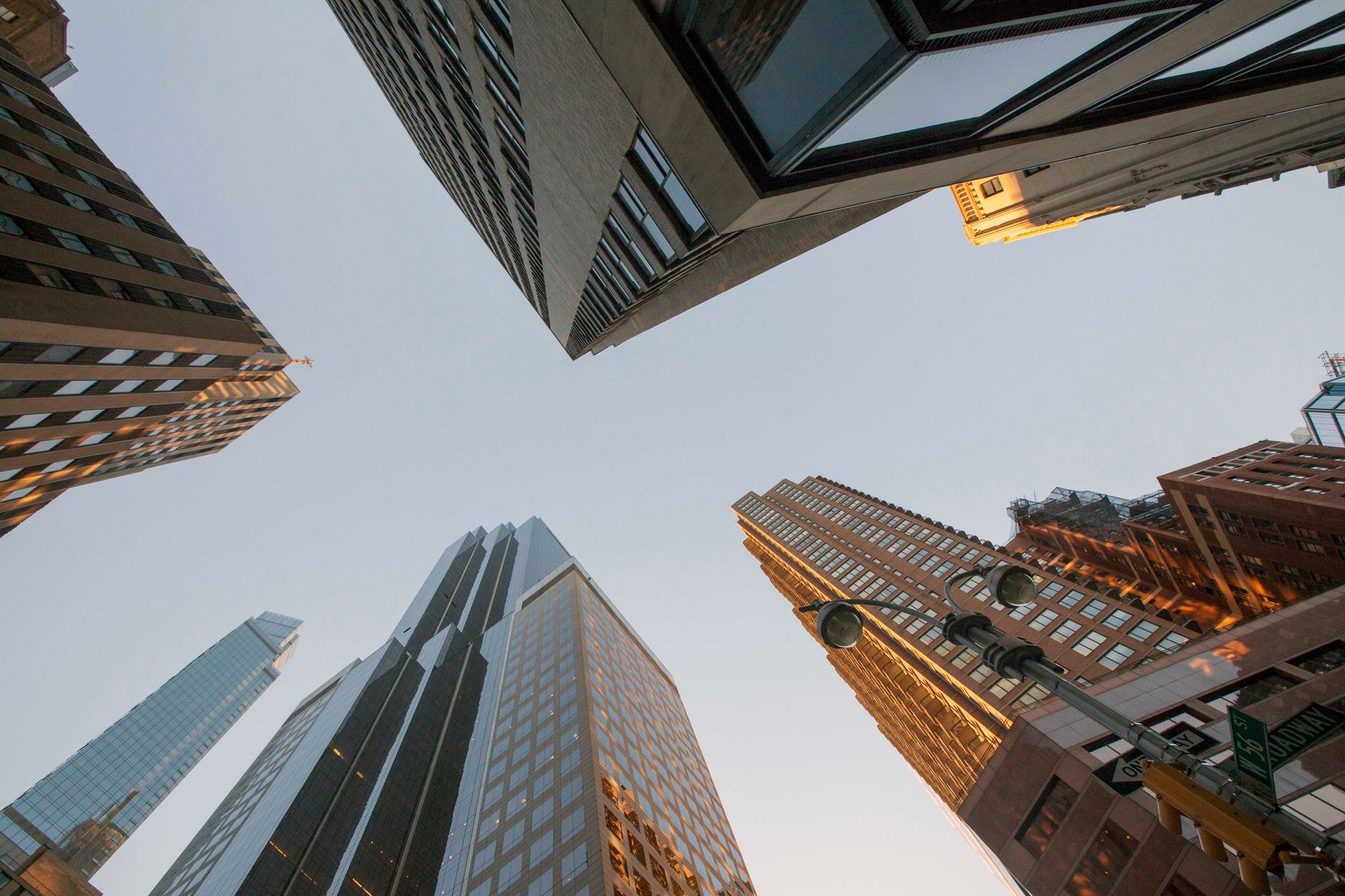 Dramatic upward view of modern skyscrapers creating an urban canyon against a clear sky.