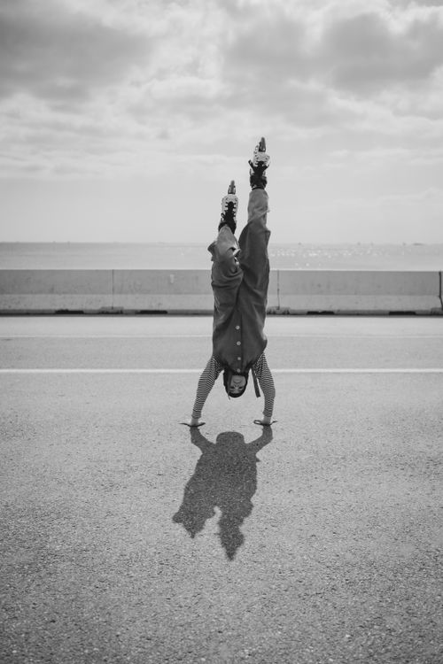 Free Monochrome image of a woman doing a handstand on roller skates on an open road. Stock Photo