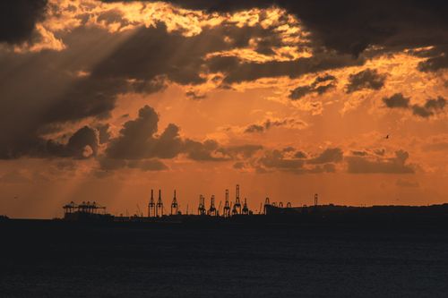 Free A striking industrial silhouette against a dramatic orange and yellow sunset sky. Stock Photo