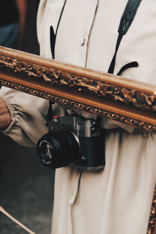Free Detail of a camera hanging on a person's neck, framed artistically for a creative touch. Stock Photo