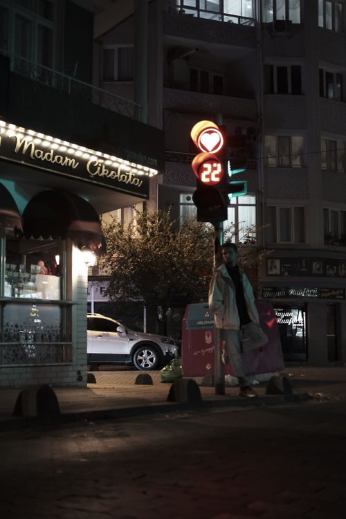 Free A city street at night with a pedestrian waiting at a traffic light showing 22 seconds. Stock Photo