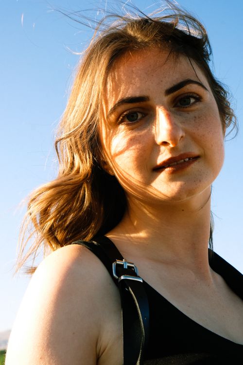 Free Close-up portrait of a smiling woman enjoying sunlight with tousled hair, creating a warm, vibrant vibe. Stock Photo
