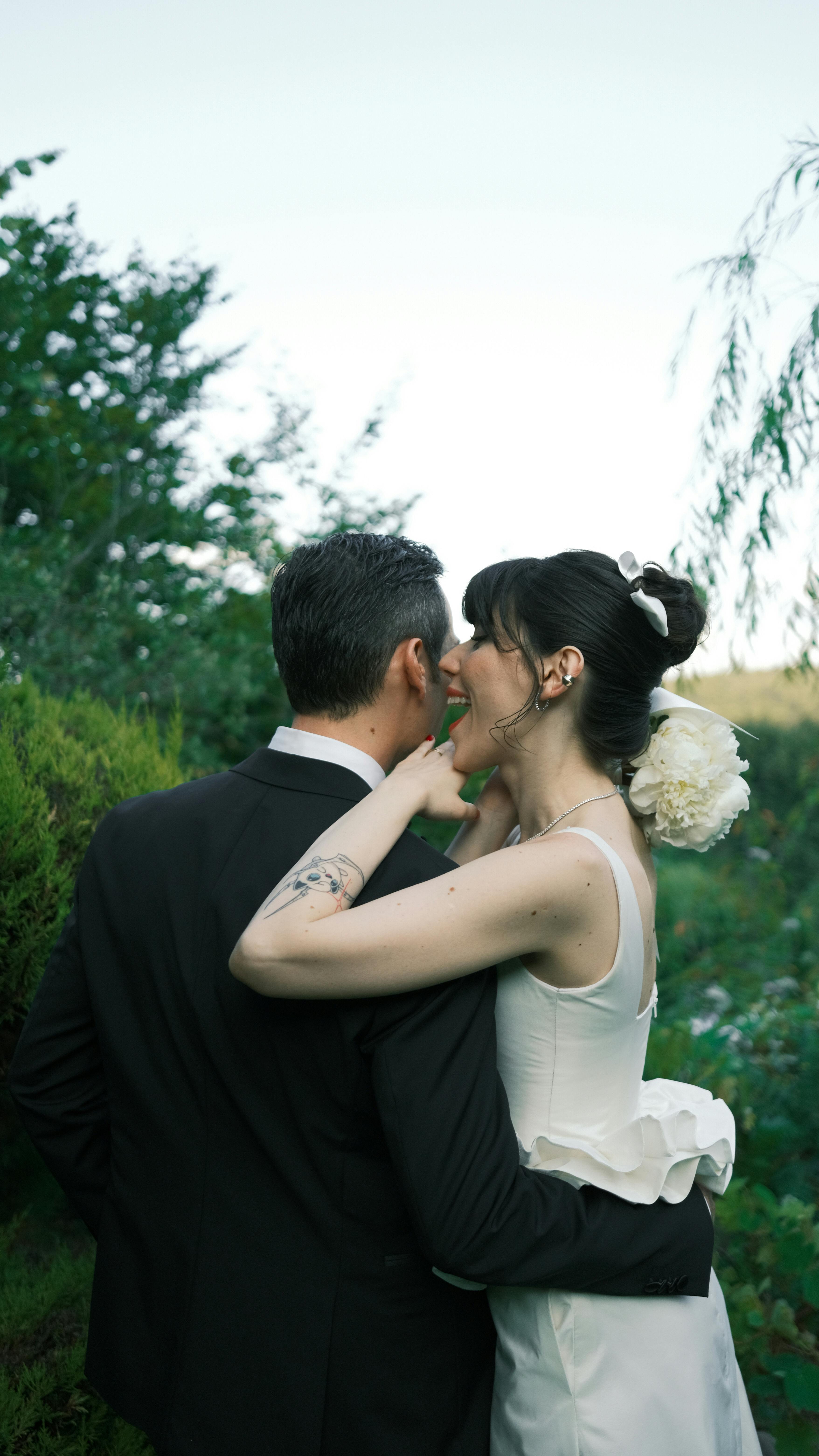 A joyous bride and groom share a romantic embrace in a lush garden, celebrating their wedding day.
