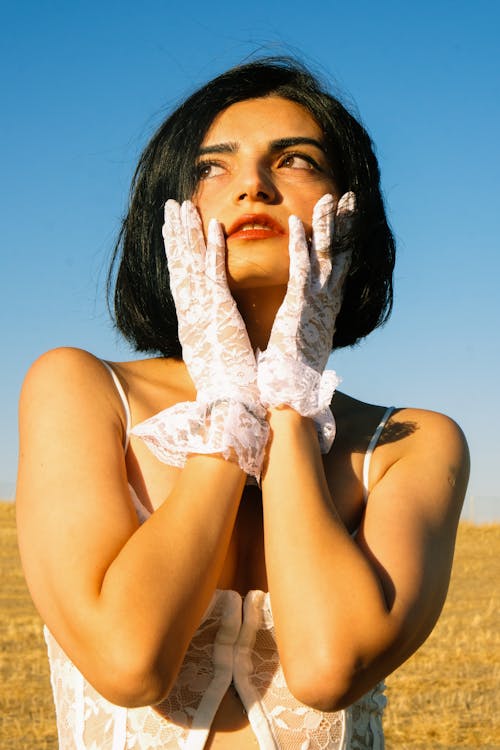 Young Woman in a White Top and Gloves Standing Outside in Sunlight