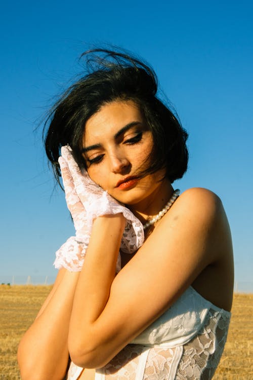 Young Brunette Woman in White Lace Gloves Corset Top Posing in a Field