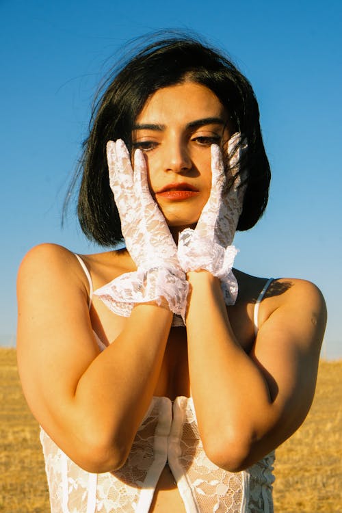 Young Woman in a White Top and Gloves Standing Outside in Sunlight