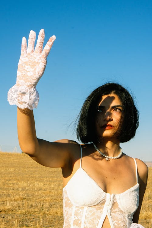Young Woman in a White Top and Gloves Standing Outside in Sunlight