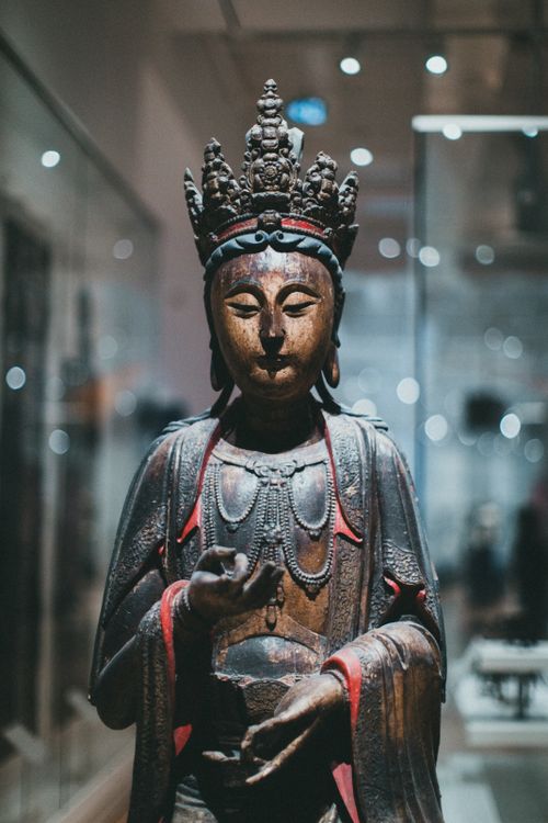 Free Wooden Buddhist statue with intricate carvings on display in a museum, showcasing spiritual artistry. Stock Photo