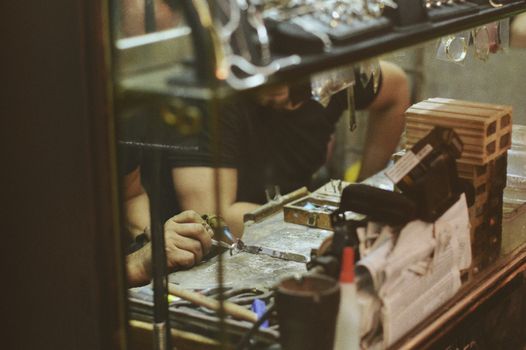 Close-up of an artisan at work in a jewelry workshop, focusing on craftsmanship and tools.