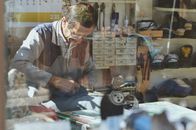 An experienced shoemaker working in a traditional workshop, surrounded by tools and materials.
