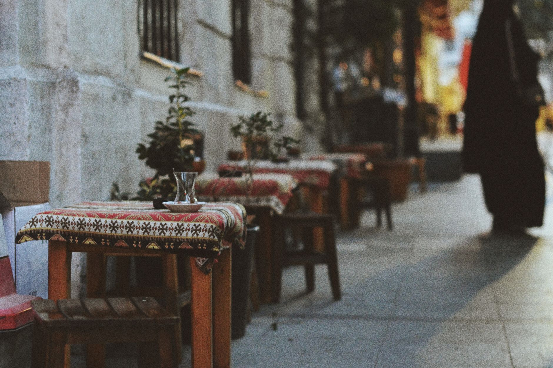 Traditional tables with patterned cloths in a quaint alleyway cafe setting.