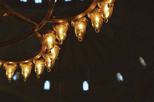 Free Close-up of a luxurious bronze chandelier with glowing bulbs in an ornate interior. Stock Photo