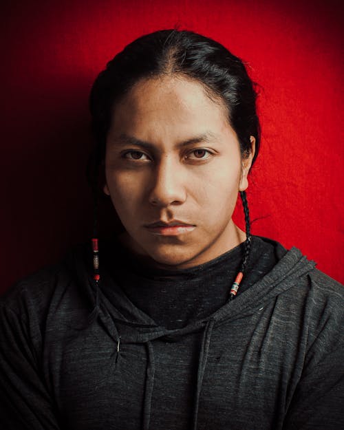 Portrait of a Man with Long Hair Standing against a Red Wall 