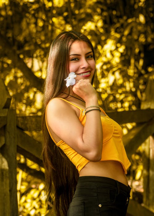 Young Woman in Yellow Strap Top Posing with a White Flower