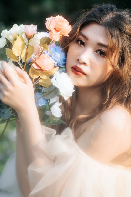Young woman in a tulle dress holding a colorful flower bouquet outdoors, exuding grace and charm.