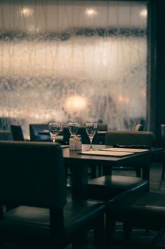Elegant, dimly lit restaurant setting with wine glasses and soft lighting for a tranquil atmosphere.