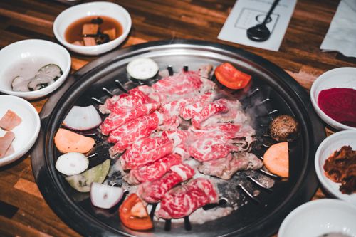 Free Delicious marbled beef slices grilling on a Korean BBQ with assorted side dishes. Stock Photo