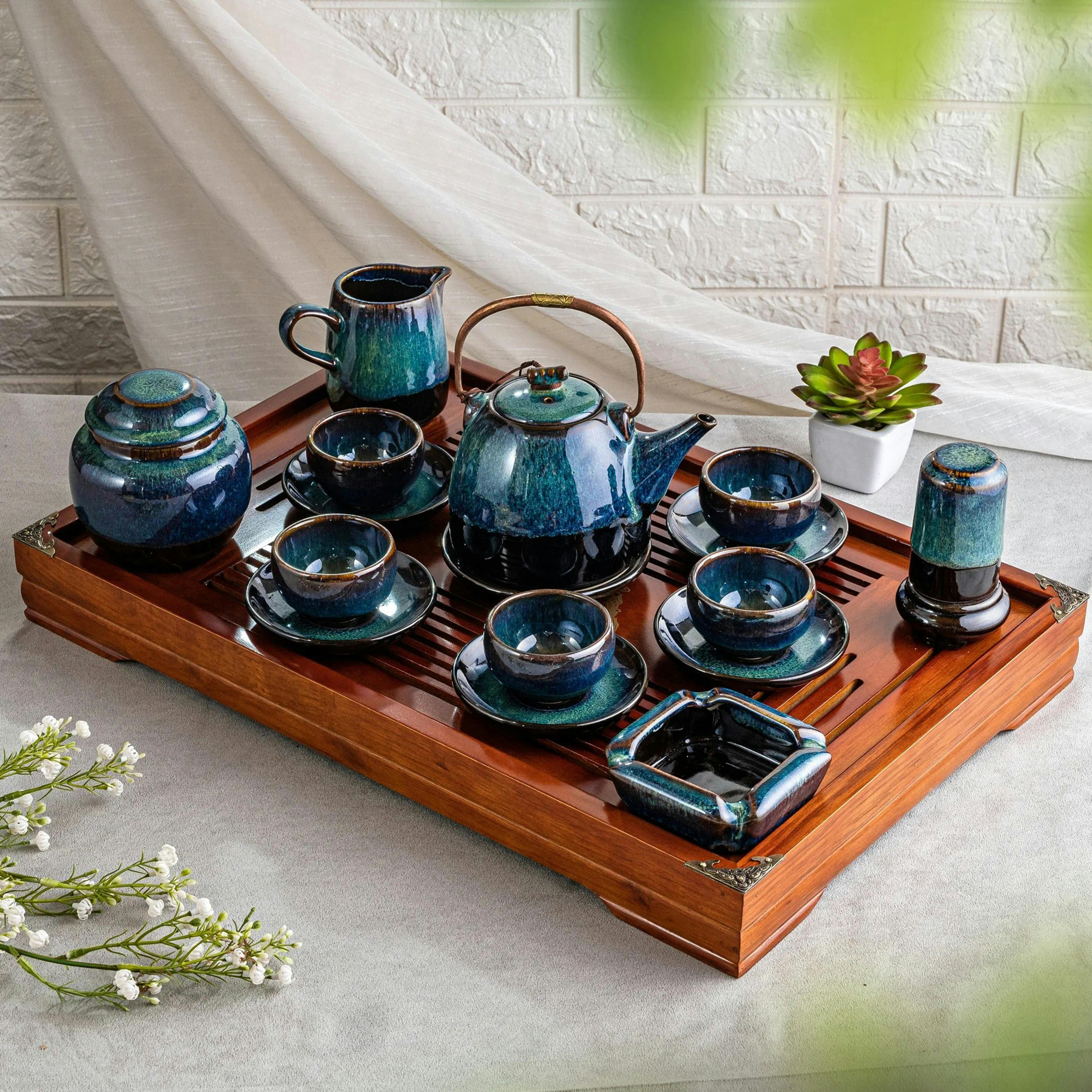 Beautiful ceramic tea set arranged on a traditional wooden tray indoors.
